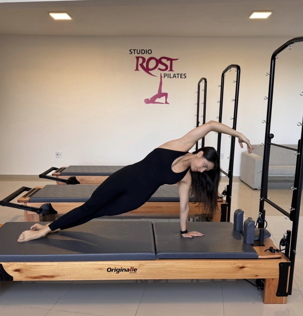 Larissa fazendo prancha lateral no Reformer do Studio Rost Pilates
